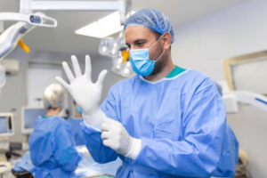 medico chirurgo che si infila i guanti in sala operatoria 